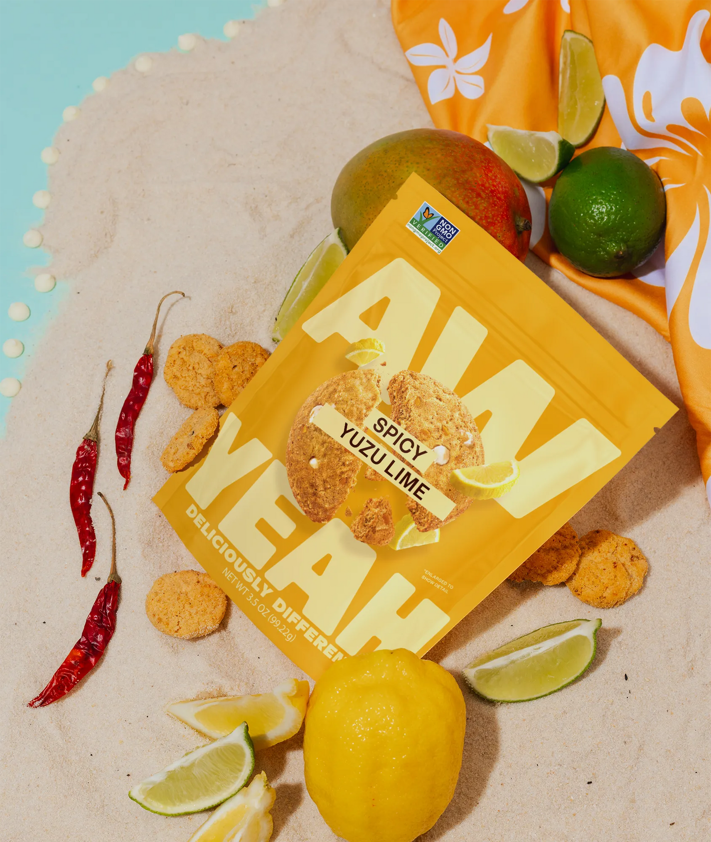 gluten free non GMO sweet and spicy cookies-Aw Yeah Spicy Yuzu Lime cookies package with yuzu, limes, mango, and red peppers on the beach